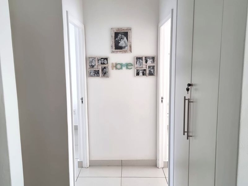 A bright, clean hallway featuring neutral tiled flooring and integrated floor-to-ceiling built-in cupboards for storage.