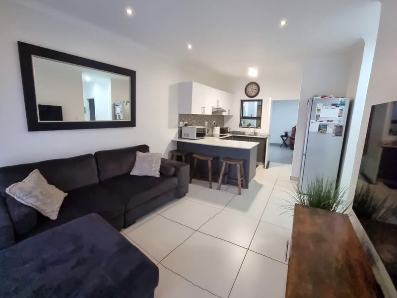 Open-plan living area featuring a modern kitchen with built-in cabinetry, a breakfast island, and tiled flooring throughout.