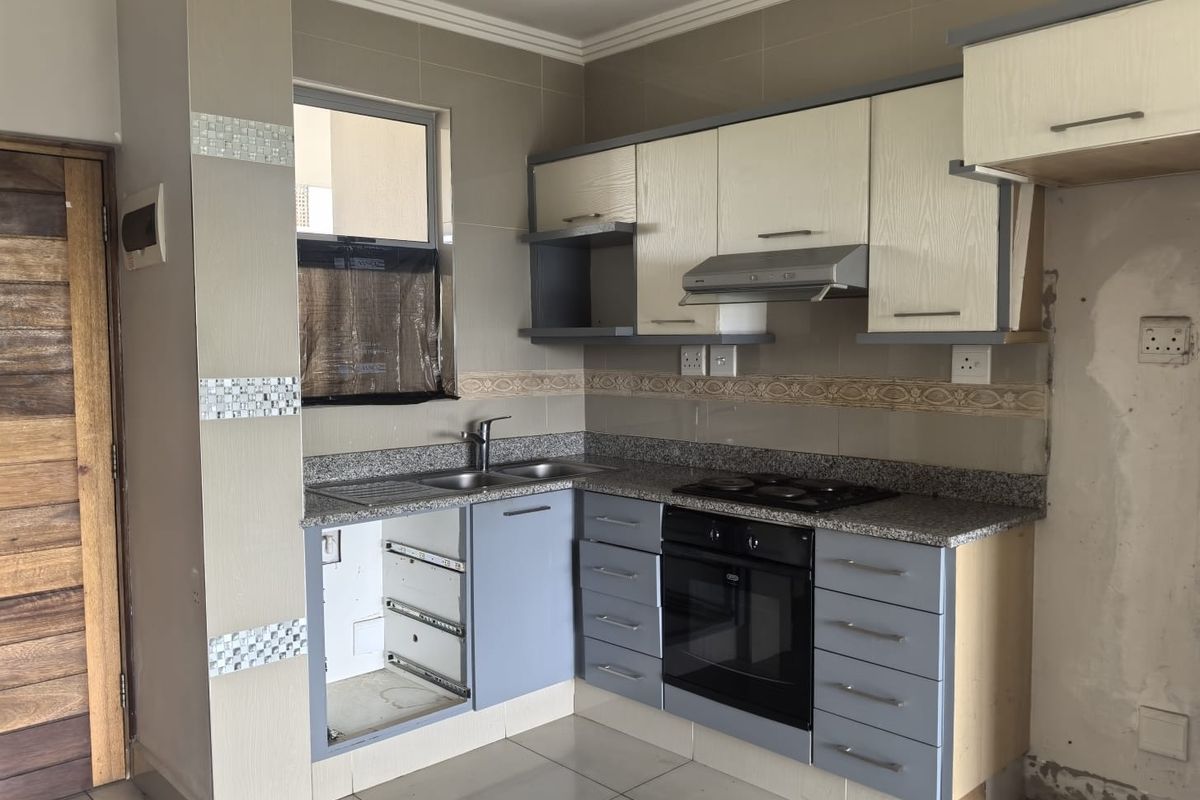 Kitchen featuring granite countertops, built-in oven, hob, and extractor fan, with some cabinetry requiring repair and wall finishing needed.
