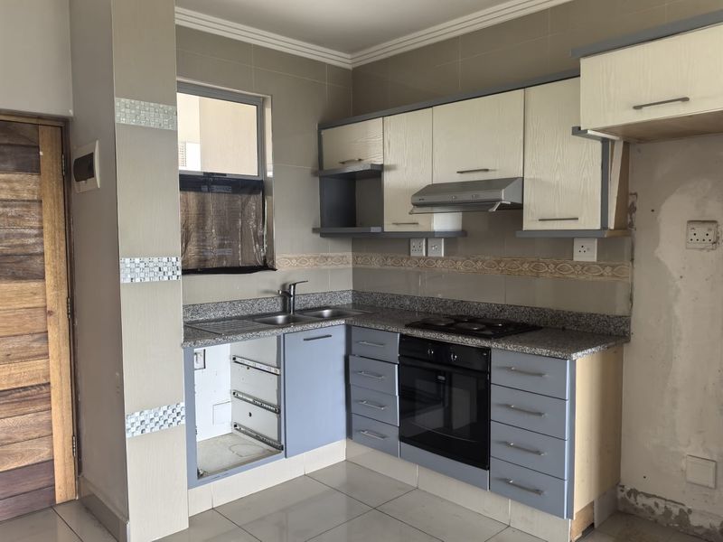 Kitchen featuring granite countertops, built-in oven, hob, and extractor fan, with some cabinetry requiring repair and wall finishing needed.