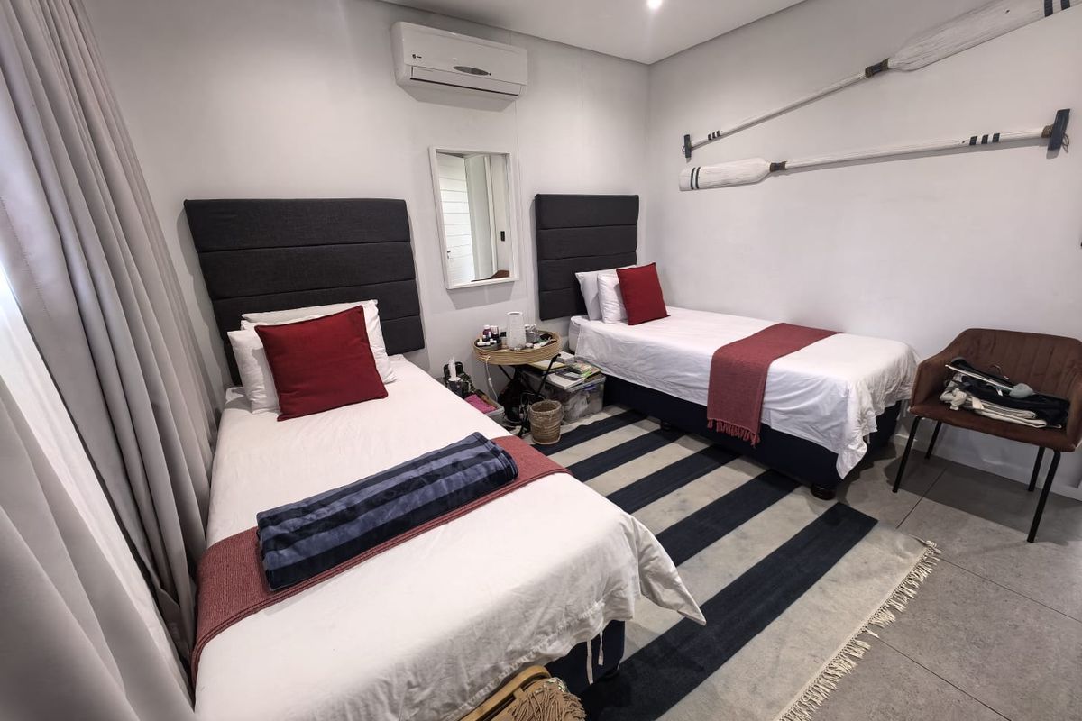 A well-maintained bedroom featuring tiled flooring, recessed downlighting, and a wall-mounted split-system air conditioning unit.