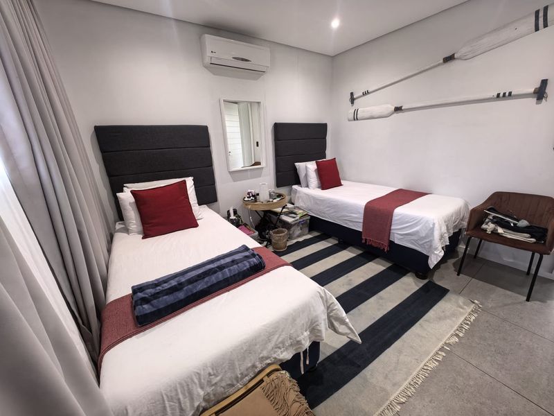 A well-maintained bedroom featuring tiled flooring, recessed downlighting, and a wall-mounted split-system air conditioning unit.
