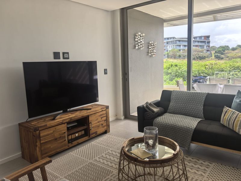 A bright living room featuring large sliding glass doors that open onto a balcony, providing natural light and views of the surrounding area.