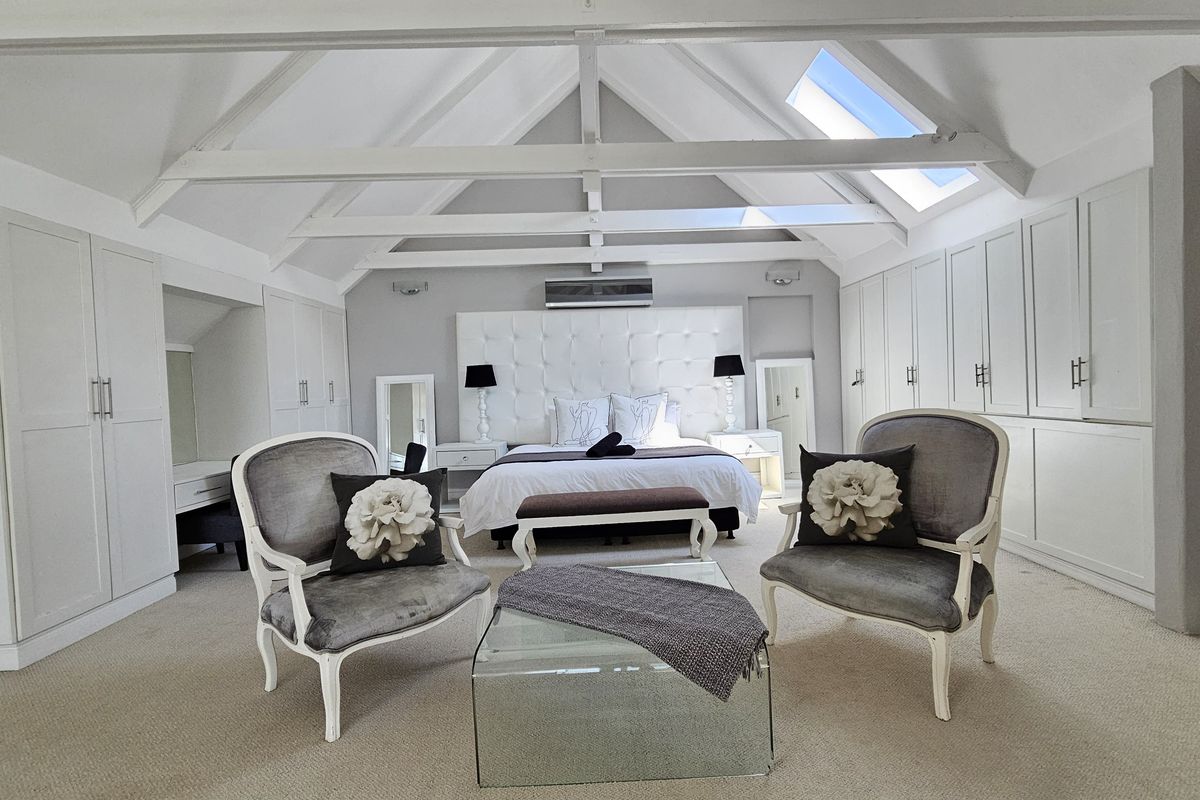 Spacious penthouse bedroom featuring a vaulted ceiling with exposed beams, integrated skylights, and extensive built-in cabinetry for ample storage.