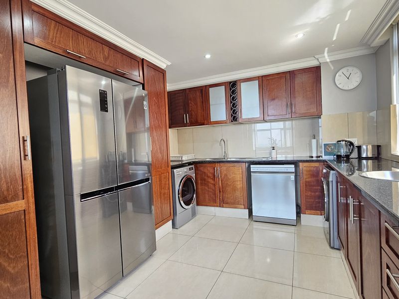 A well-appointed kitchen featuring rich wooden cabinetry, granite countertops, integrated appliances, and tiled flooring, offering a functional and classic culinary space.