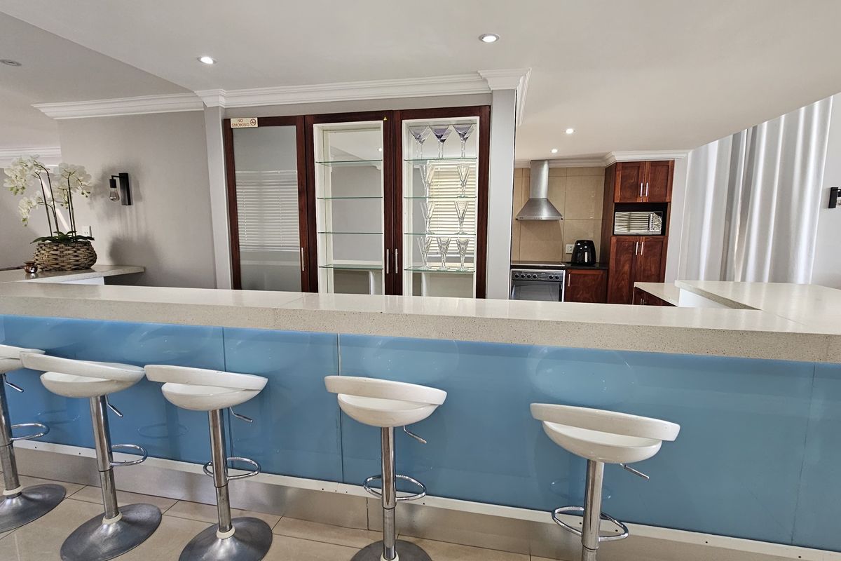 Modern kitchen featuring a breakfast bar with stone countertop, built-in glass display cabinets, and integrated stainless steel appliances.
