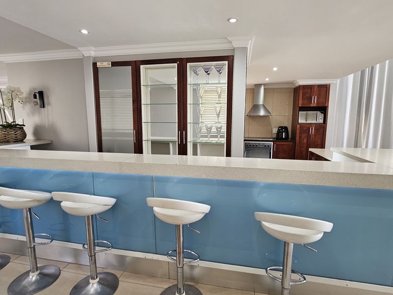 Modern kitchen featuring a breakfast bar with stone countertop, built-in glass display cabinets, and integrated stainless steel appliances.
