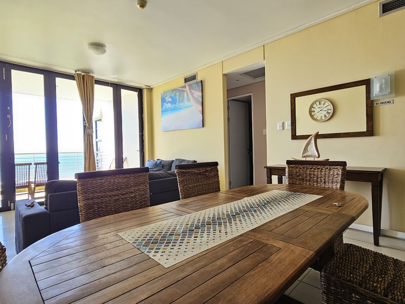 Open-plan living and dining area featuring large sliding glass doors that provide natural light and access to a balcony with ocean views.