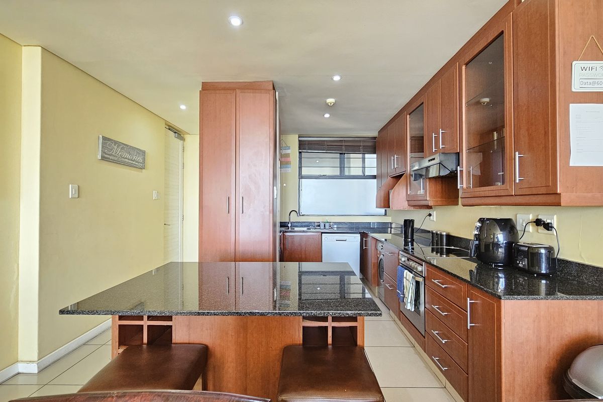 A functional kitchen featuring wooden cabinetry, granite countertops, a central island, and integrated appliances, offering a practical layout for daily use.