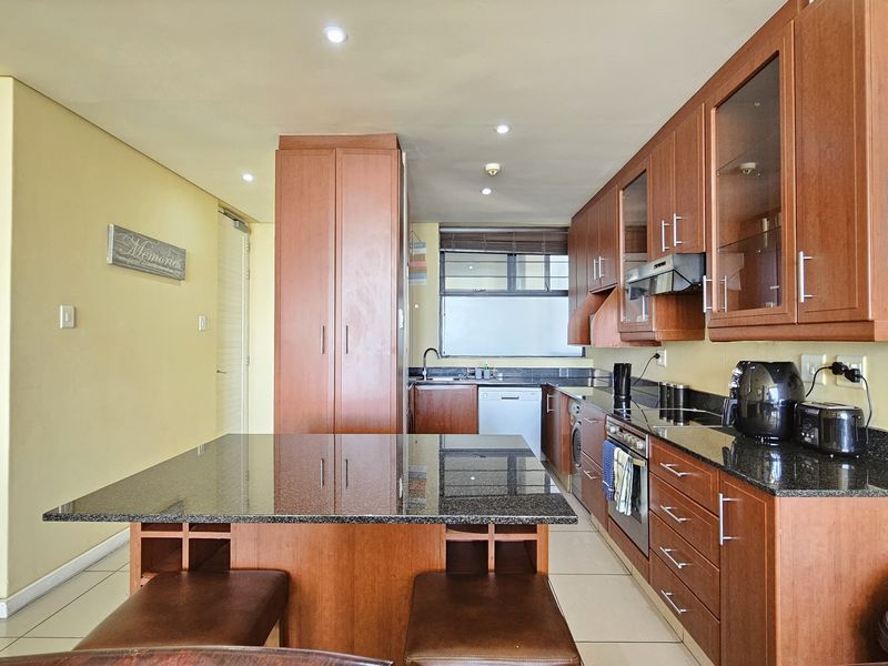 A functional kitchen featuring wooden cabinetry, granite countertops, a central island, and integrated appliances, offering a practical layout for daily use.