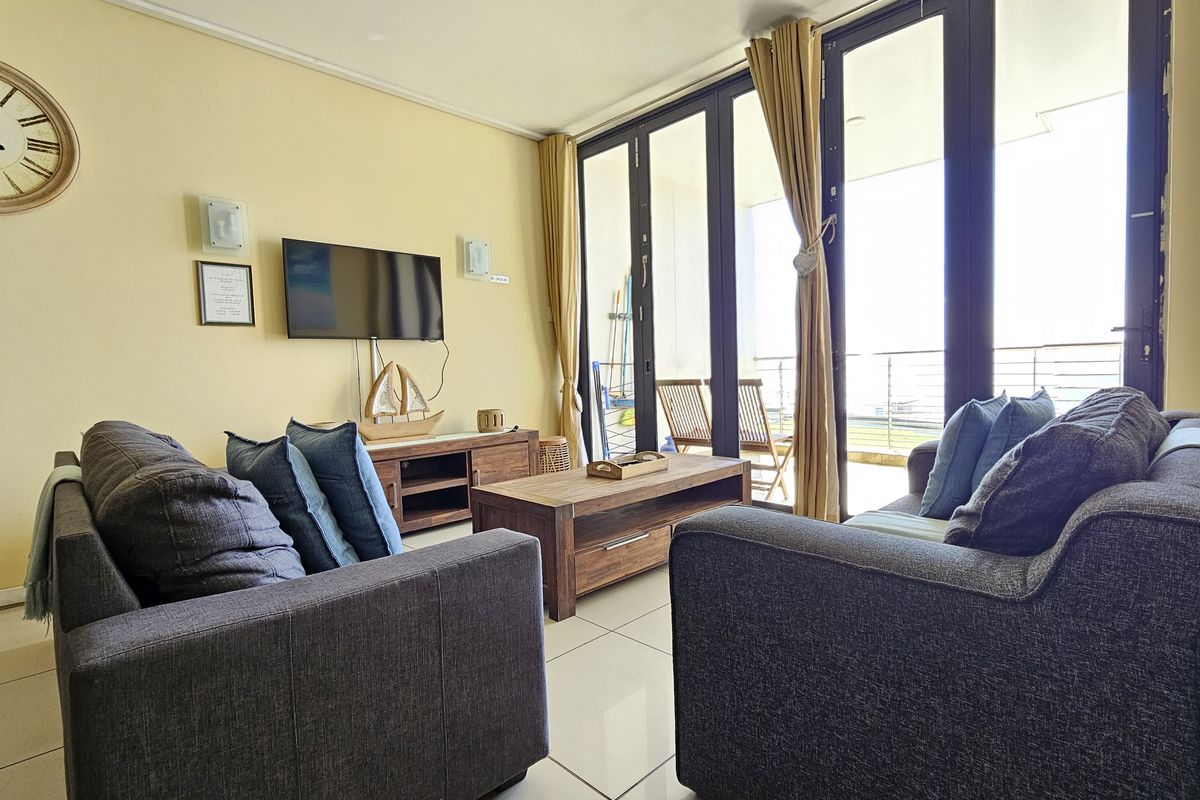 A bright living room featuring large glass sliding doors that provide access to an outdoor balcony and allow for ample natural light.