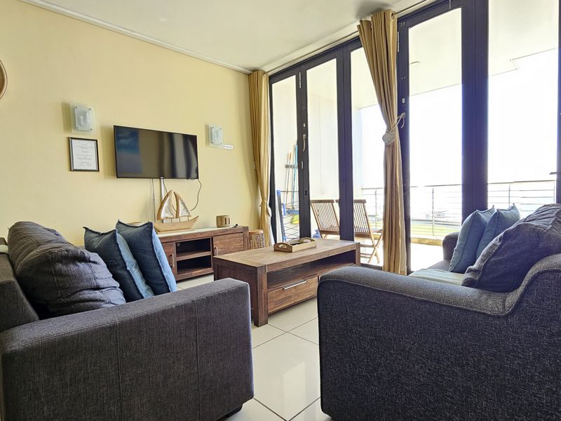 A bright living room featuring large glass sliding doors that provide access to an outdoor balcony and allow for ample natural light.
