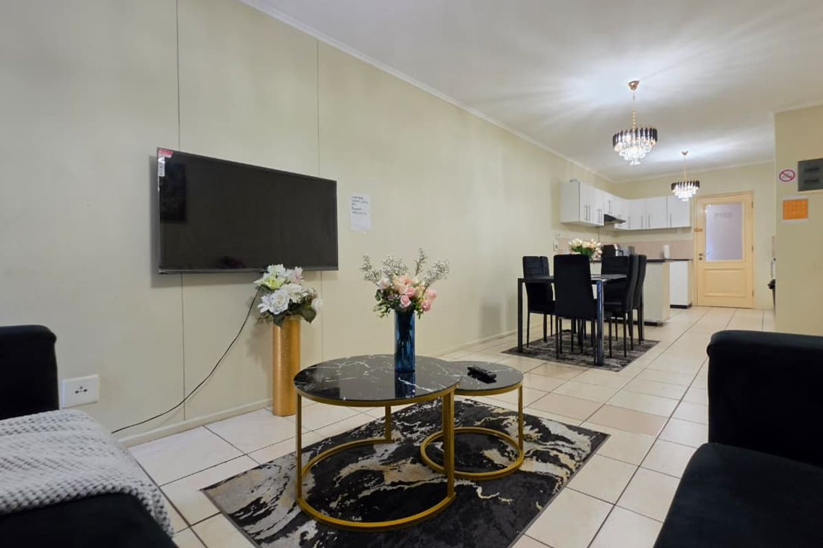 An open-plan living and dining area featuring tiled floors, a functional kitchen with built-in cabinetry, and a seamless flow between the lounge and dining space.