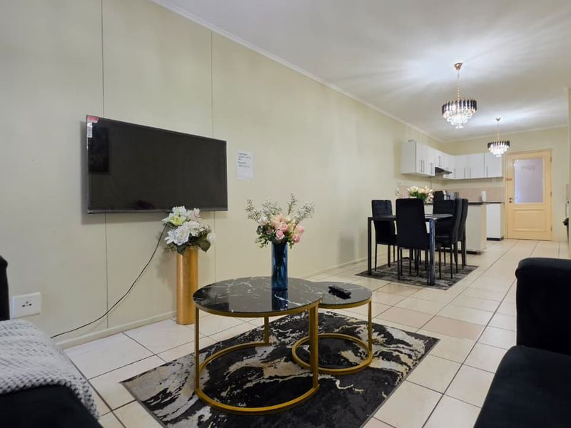 An open-plan living and dining area featuring tiled floors, a functional kitchen with built-in cabinetry, and a seamless flow between the lounge and dining space.