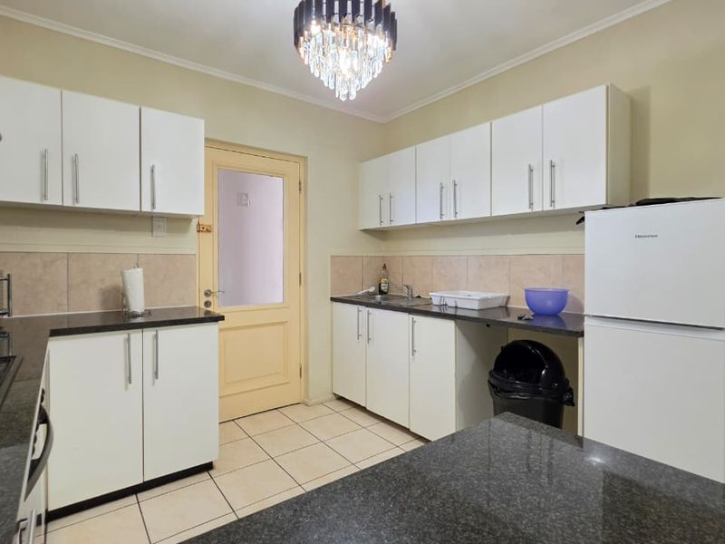 A functional kitchen featuring white cabinetry, dark granite countertops, tiled backsplash, and ceramic flooring, providing a clean and practical workspace.