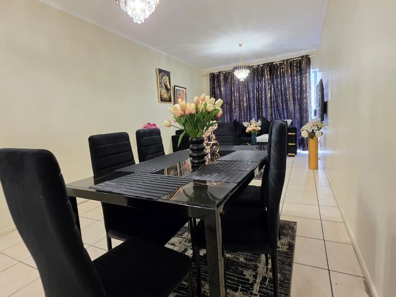 An open-plan living and dining area featuring tiled flooring and elegant crystal chandeliers, creating a bright and cohesive space.