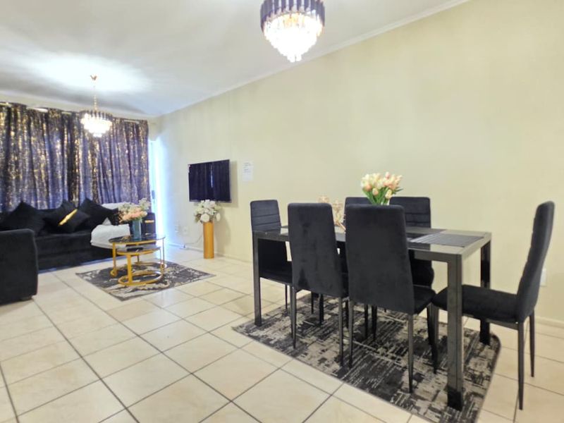 An open-plan living and dining area featuring neutral tiled flooring and decorative crystal chandeliers, providing a versatile space for relaxation and entertaining.