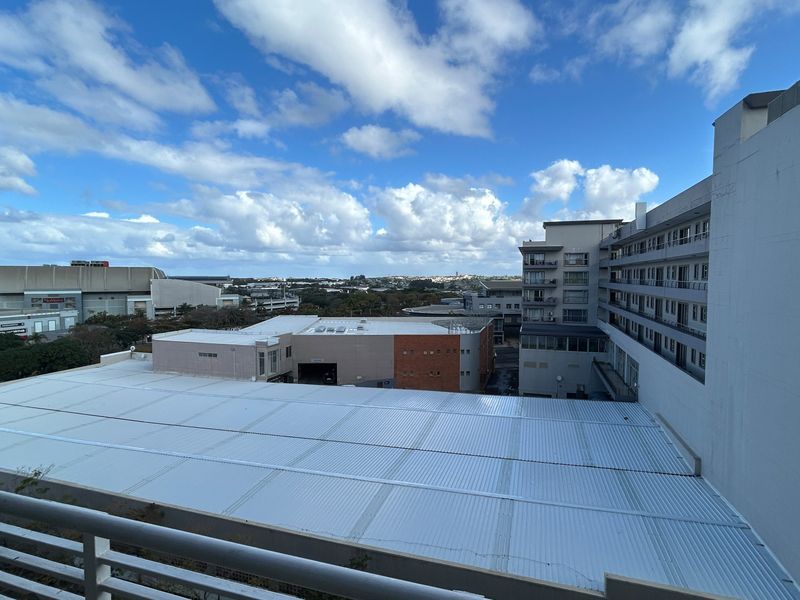 An elevated urban view overlooking surrounding commercial buildings and rooftops from a balcony.