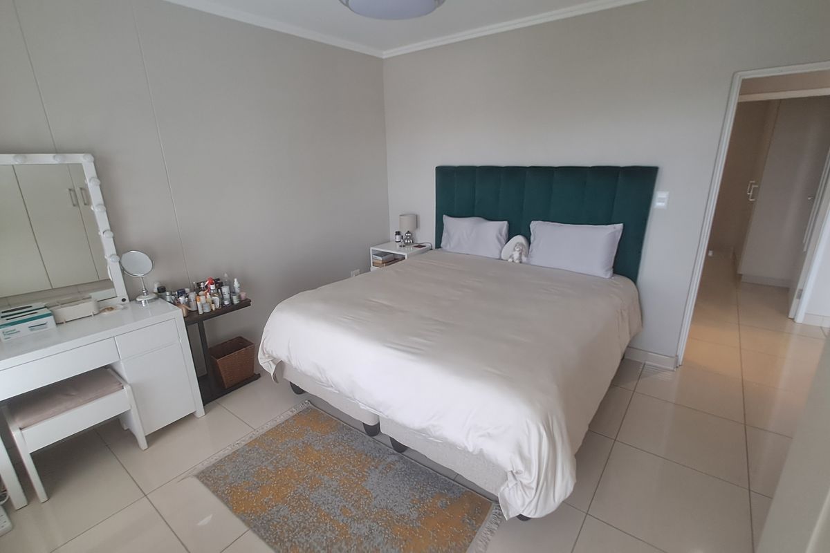 A well-maintained bedroom featuring neutral wall tones, tiled flooring, and built-in cupboard storage, offering a clean and functional living space.