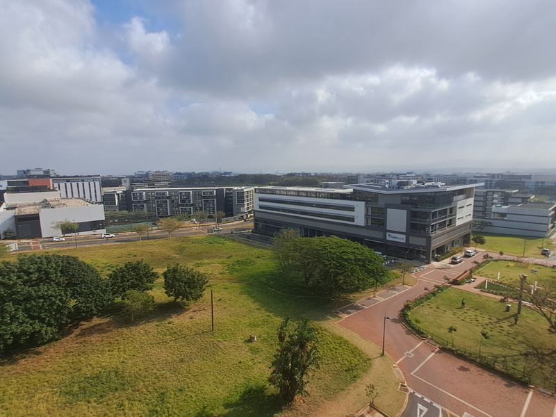 Elevated panoramic view overlooking the surrounding urban landscape, green spaces, and modern commercial buildings.