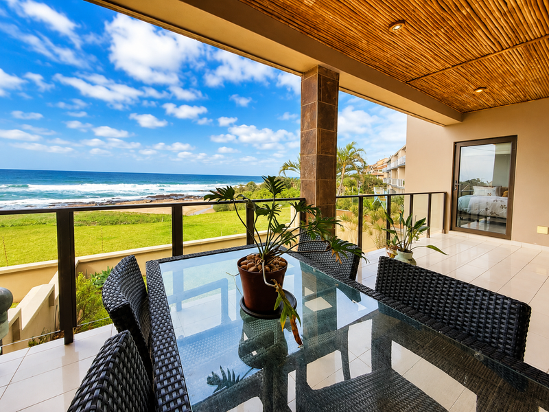 Spacious covered balcony featuring tiled flooring, a bamboo ceiling with recessed lighting, and panoramic ocean views, perfect for outdoor dining.