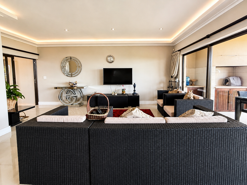 Spacious living room featuring recessed cove lighting, large sliding glass doors leading to an outdoor area, and polished tiled flooring.