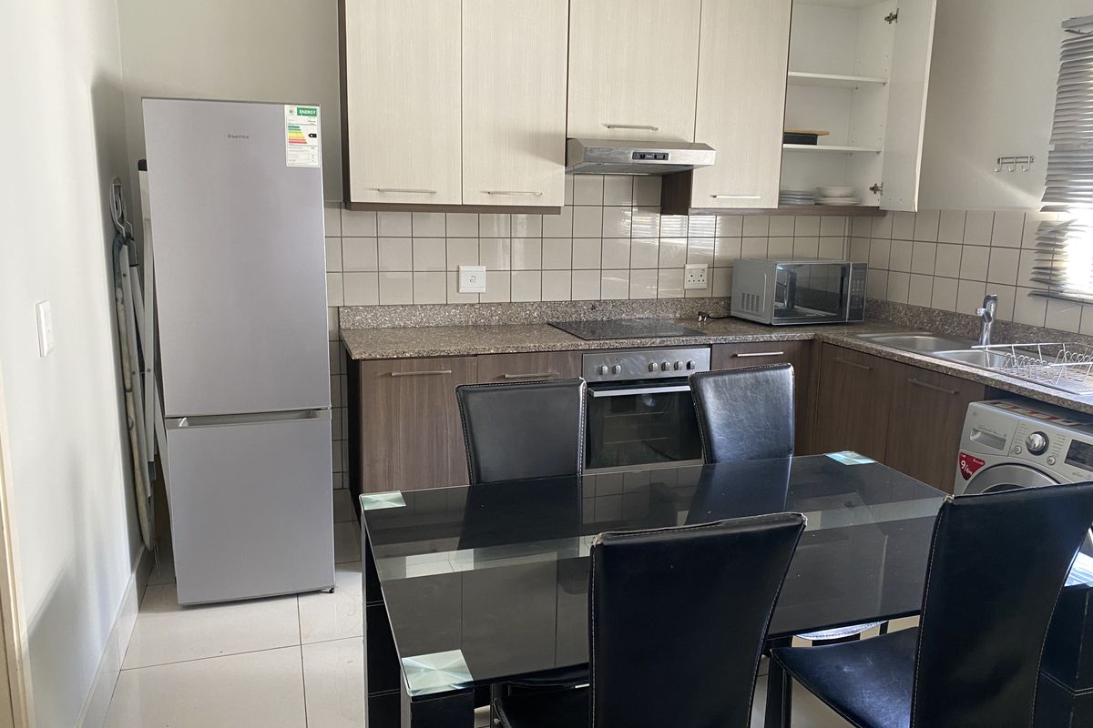 A functional kitchen featuring built-in cabinetry, granite countertops, a tiled backsplash, and integrated appliances including an oven and extractor fan.