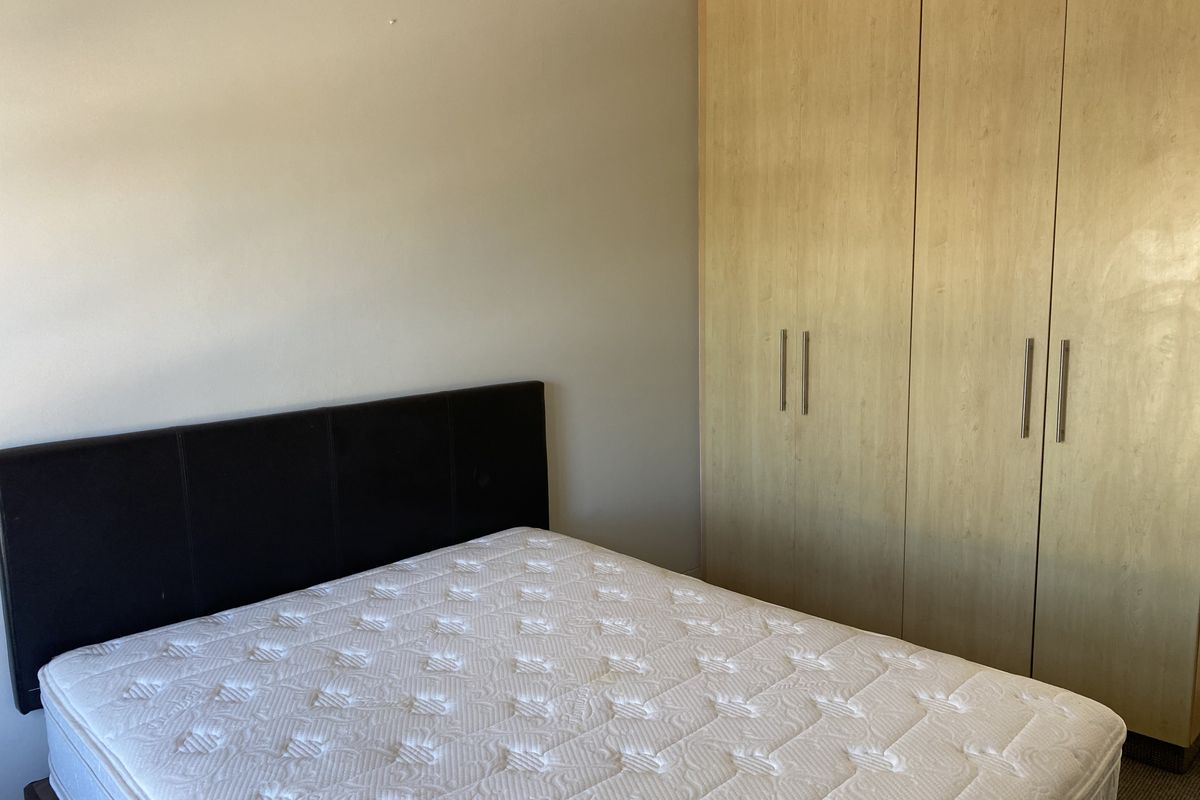 A bedroom featuring light wood-finish built-in cupboards providing ample storage space.
