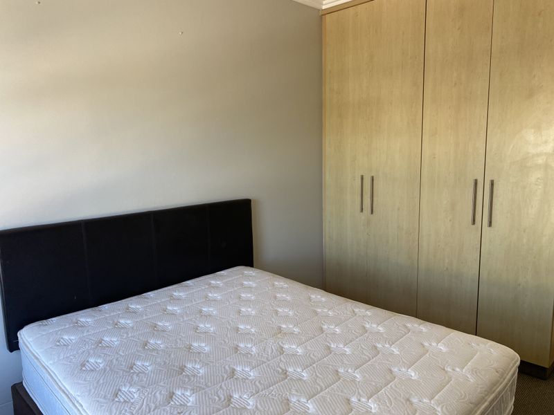 A bedroom featuring light wood-finish built-in cupboards providing ample storage space.