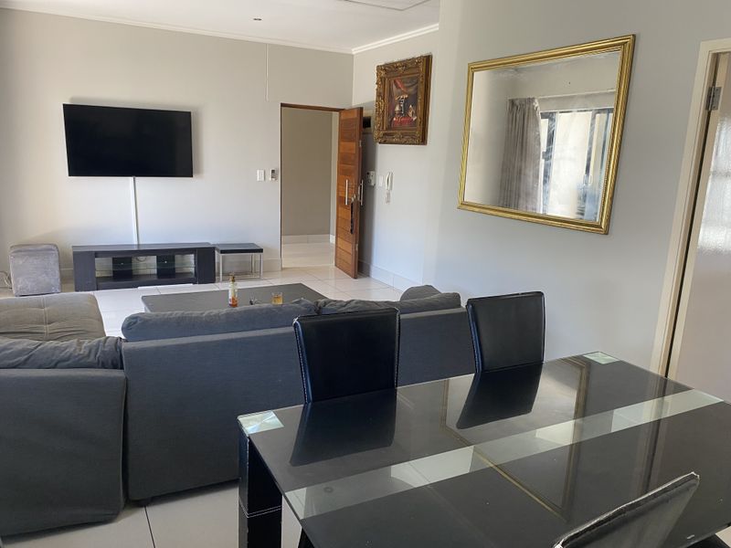 Open-plan living and dining area featuring neutral wall tones, tiled flooring, and recessed lighting, providing a functional and versatile space.