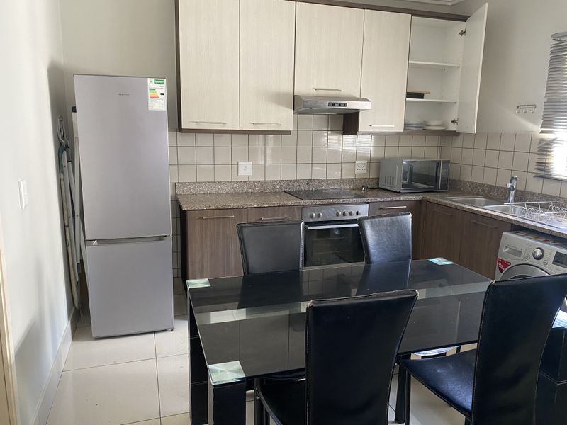 A functional kitchen featuring built-in cabinetry, granite countertops, a tiled backsplash, and integrated appliances including an oven and extractor fan.