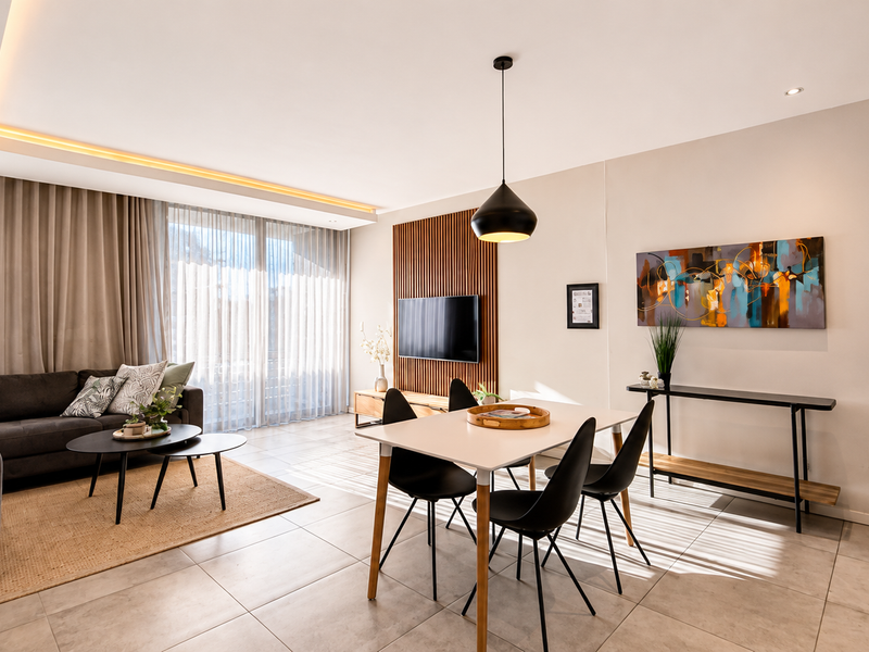 Modern open-plan living and dining area featuring tiled floors, a stylish timber slat feature wall, and recessed ceiling lighting with integrated cove illumination.