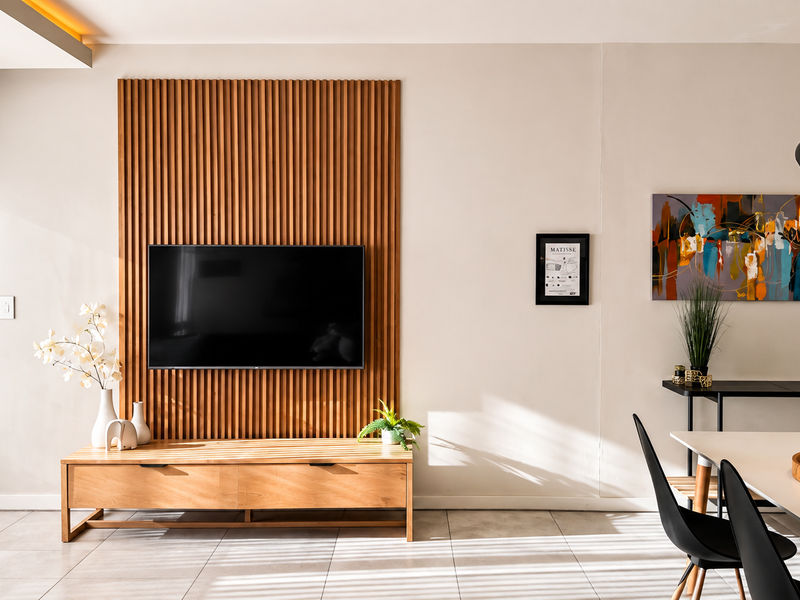 Modern living area featuring a stylish timber slat feature wall, tiled flooring, and recessed ceiling lighting, creating a warm and contemporary atmosphere.