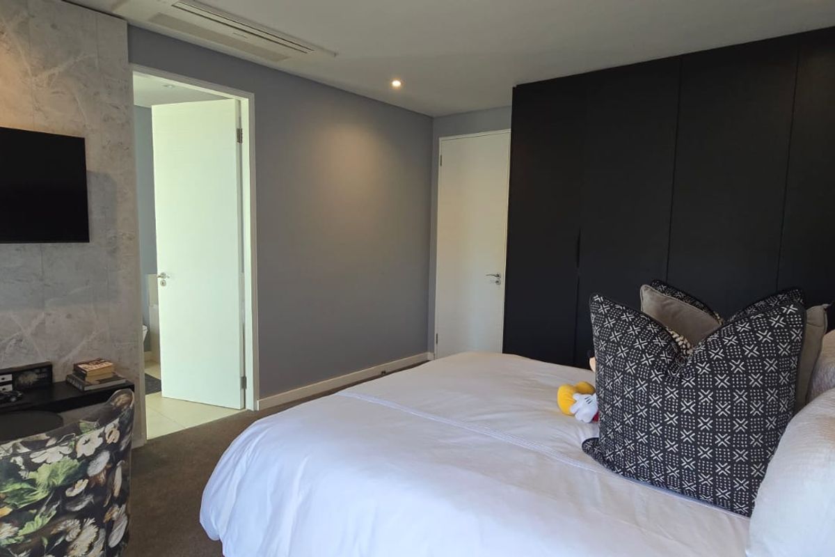 Modern bedroom featuring a stone feature wall, built-in black cabinetry, and integrated ducted air conditioning.