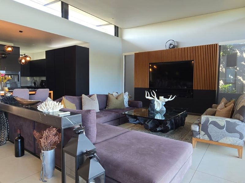 Modern open-plan living area featuring a sleek kitchen with island, slatted timber feature wall, and large sliding doors leading to outdoor space.