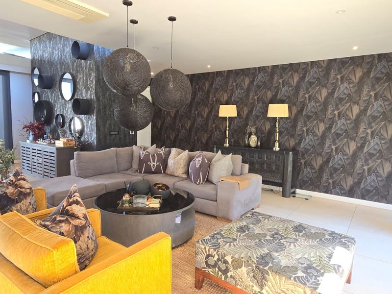 Spacious living room featuring modern tiled flooring, decorative feature wallpaper, and large sliding glass doors providing ample natural light.