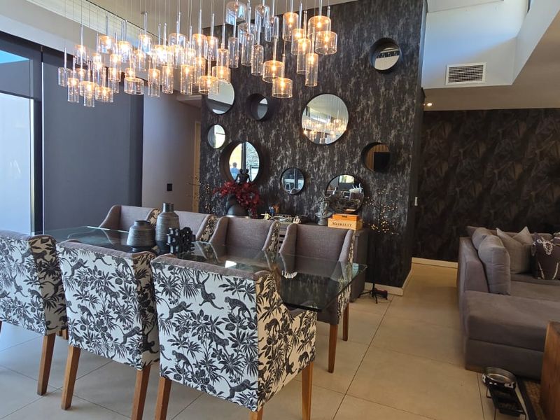 Spacious open-plan living and dining area featuring large format floor tiles, modern recessed lighting, and expansive sliding glass doors leading to the patio.