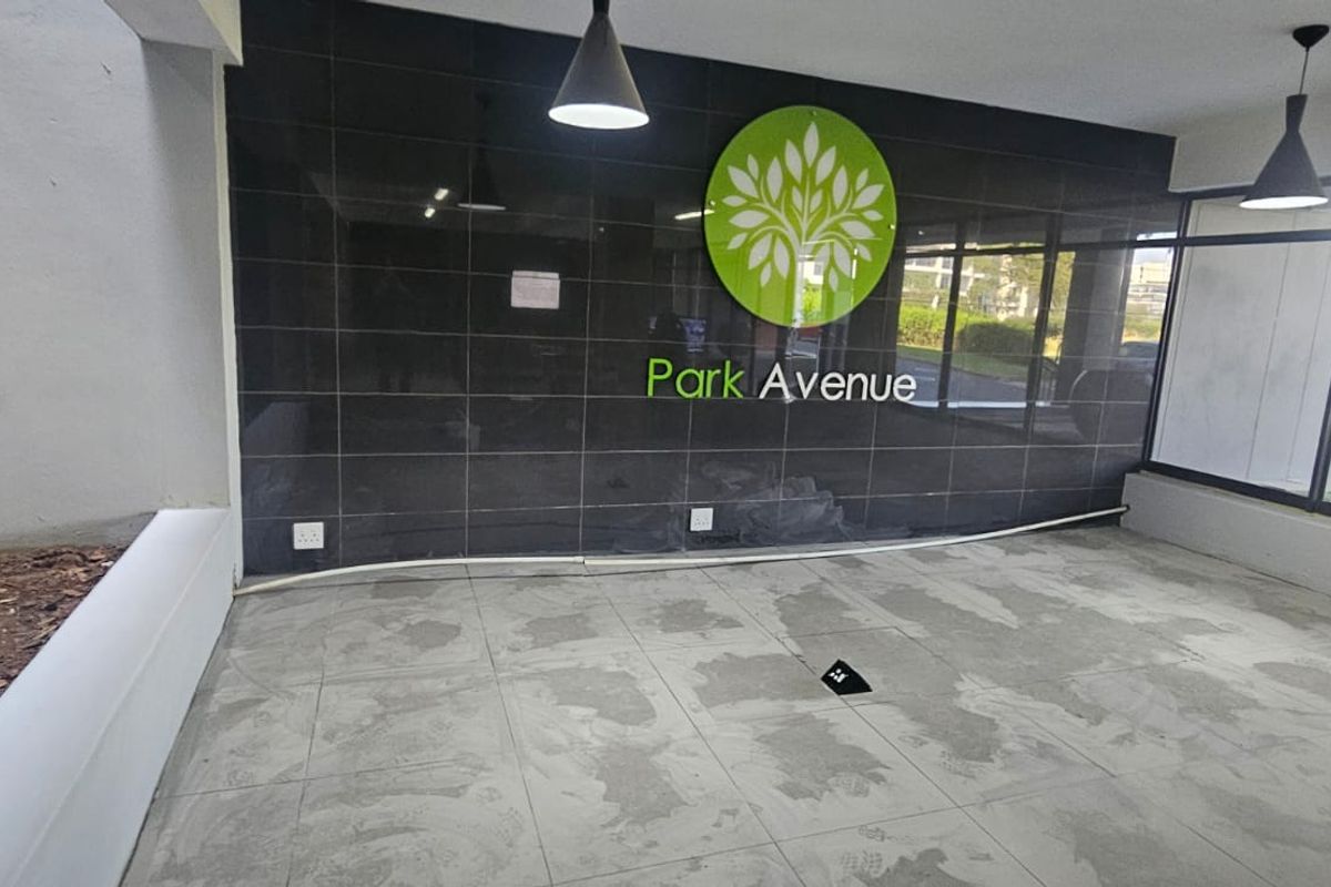 Entrance lobby area featuring a branded feature wall, large windows, and tiled flooring, currently in an unfinished state requiring completion.