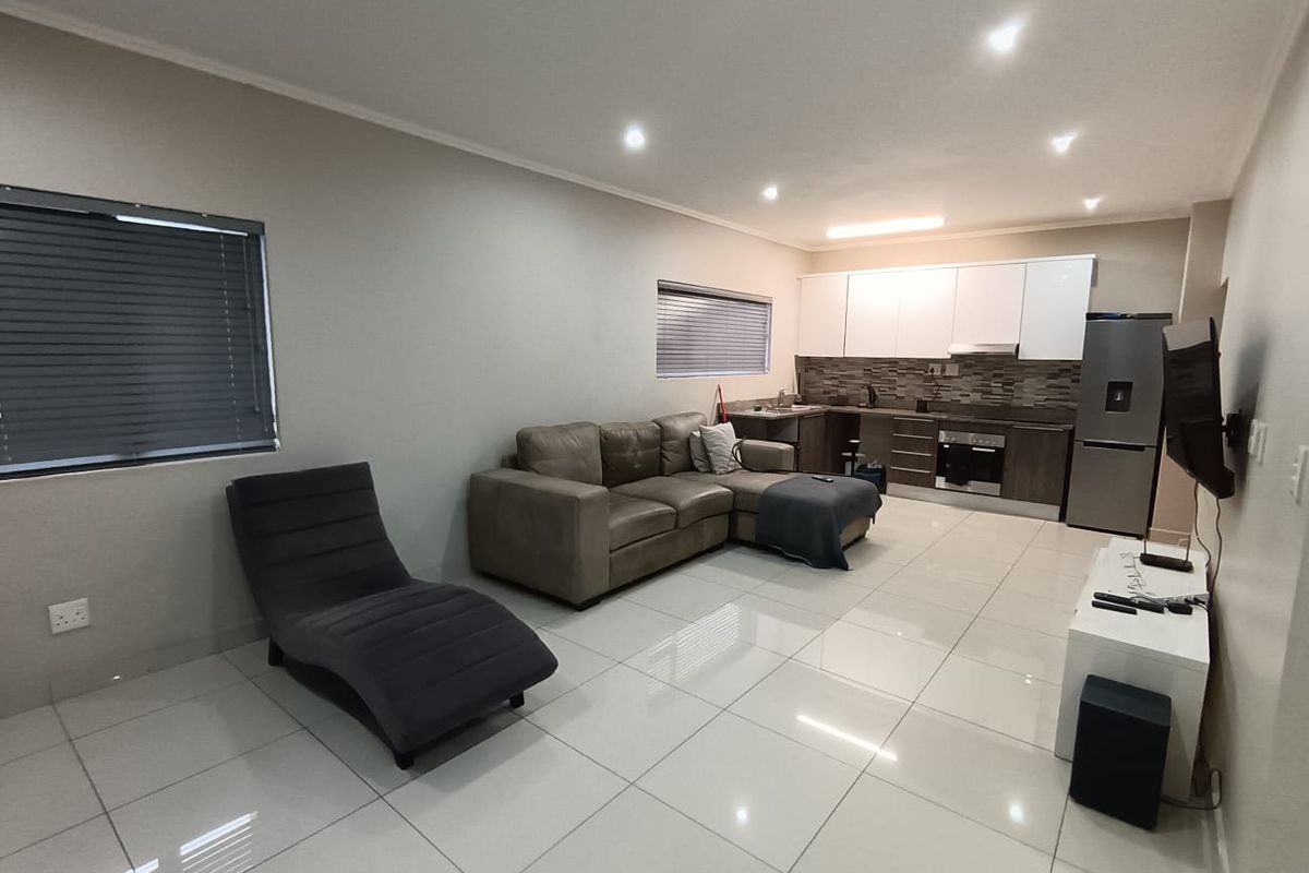 Open-plan living area featuring tiled floors, recessed lighting, and a modern kitchen with built-in cabinetry, oven, and extractor fan.
