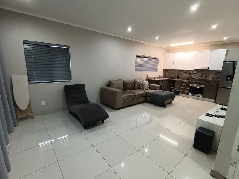 Modern open-plan living area featuring sleek tiled flooring, recessed lighting, and a contemporary kitchen with built-in cabinetry and appliances.