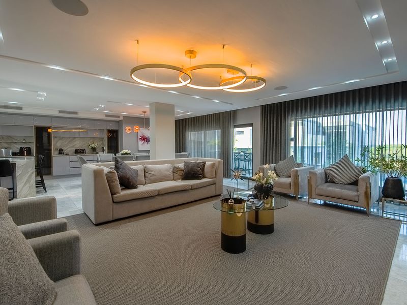 Spacious open-plan living and kitchen area featuring modern finishes, marble island, recessed lighting, and large windows with floor-to-ceiling curtains.