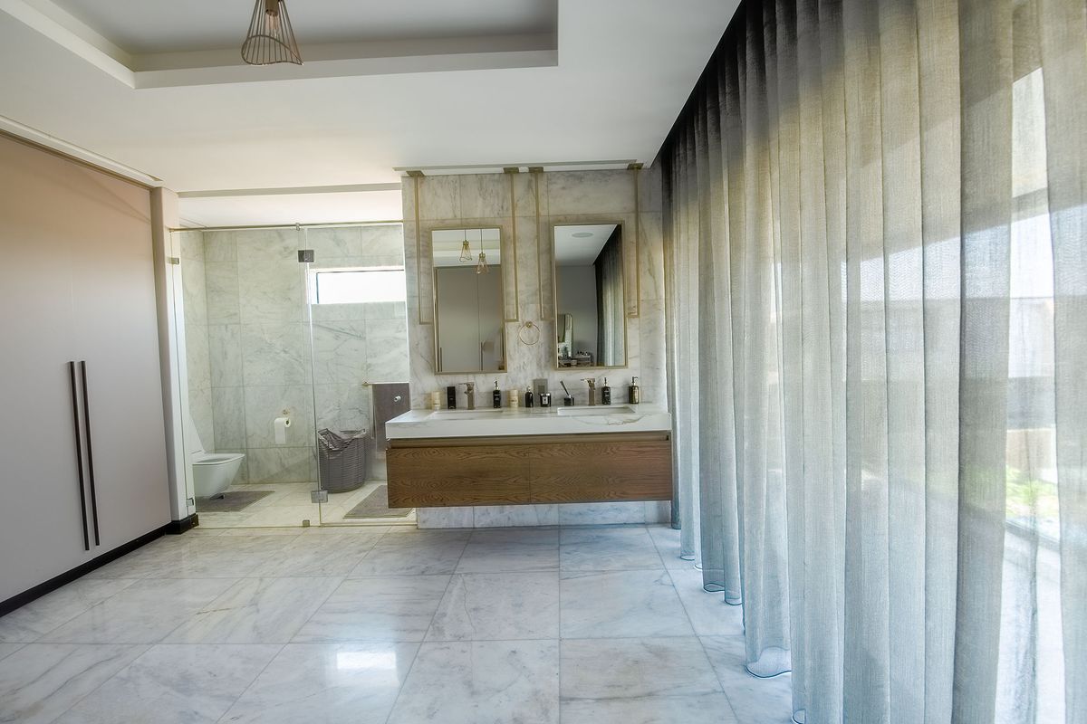 Modern luxury bathroom featuring a double vanity with marble finishes, a glass-enclosed shower, and high-end wall-mounted fixtures.