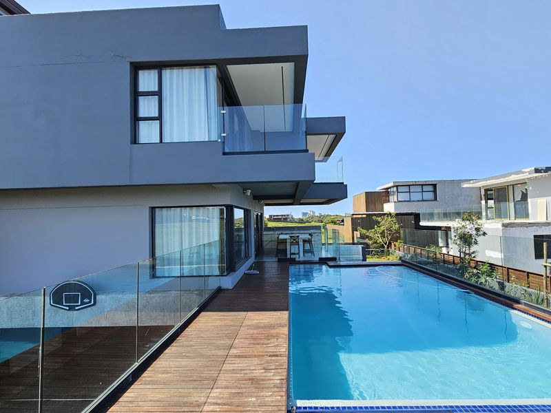 Modern multi-story home featuring a sleek swimming pool, timber decking, and glass balustrades, offering a contemporary outdoor living space.