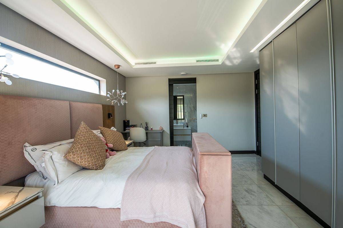 Modern bedroom featuring marble flooring, recessed ceiling lighting, a large built-in wardrobe, and a clerestory window, with direct access to an en-suite bathroom.