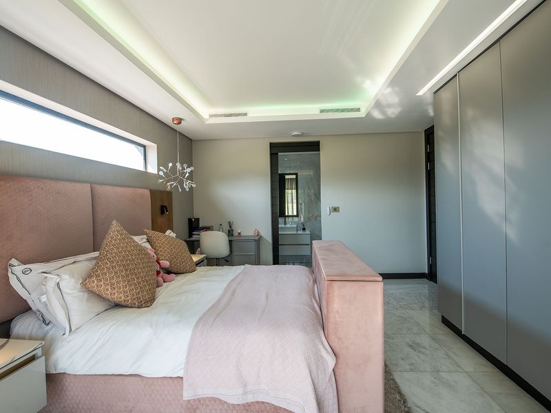 Modern bedroom featuring marble flooring, recessed ceiling lighting, a large built-in wardrobe, and a clerestory window, with direct access to an en-suite bathroom.