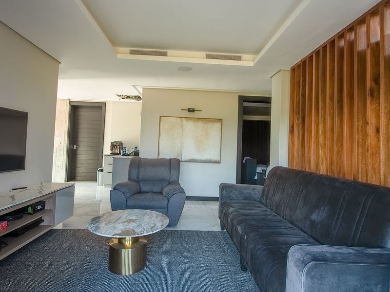 Modern living room featuring marble flooring, recessed ceiling lighting, and a decorative timber slat feature wall, providing a contemporary and comfortable living space.
