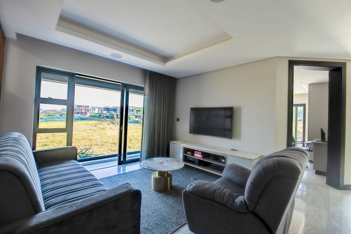 Modern living room featuring marble flooring, a recessed ceiling with integrated lighting, and large sliding glass doors providing access to the exterior.