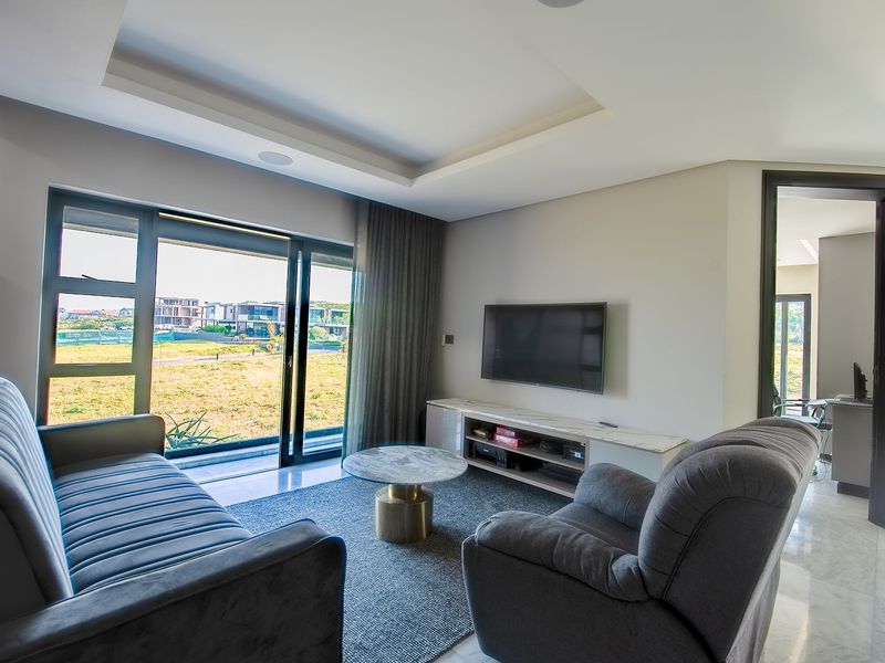 Modern living room featuring marble flooring, a recessed ceiling with integrated lighting, and large sliding glass doors providing access to the exterior.