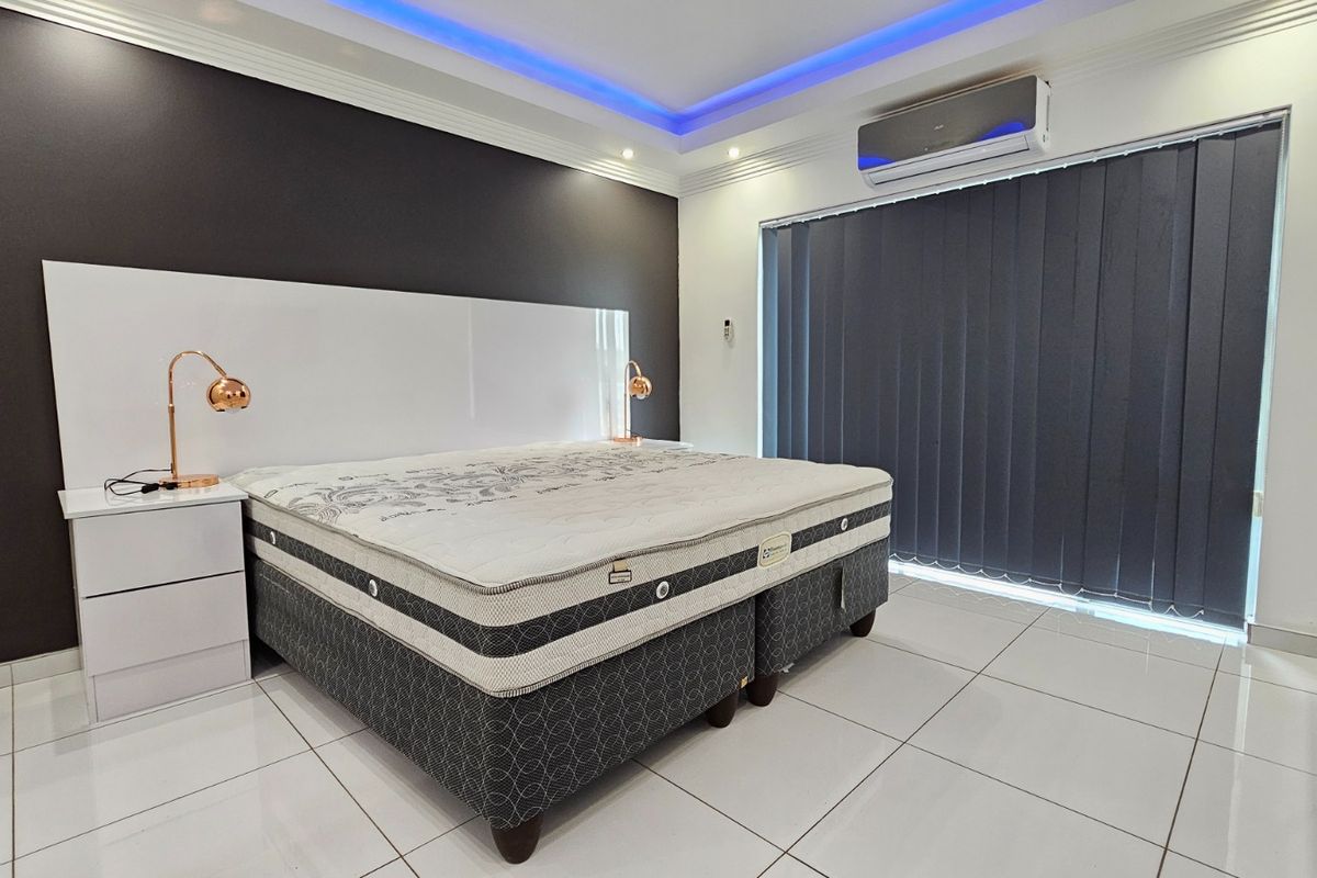 Modern bedroom featuring tiled flooring, recessed ceiling lighting, a built-in headboard, and a wall-mounted split-system air conditioner.