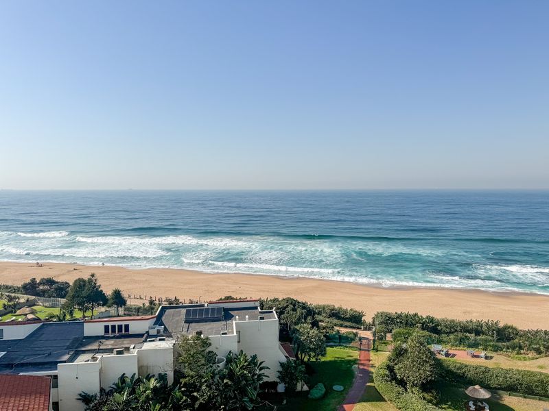 A stunning elevated view overlooking the sandy beach and ocean, showcasing the coastal location of the property.
